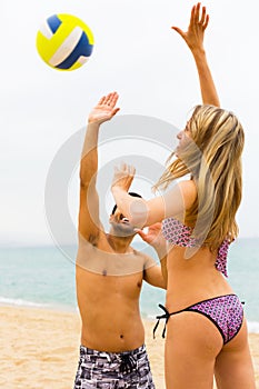 Smiling couple playing with a ball at beach
