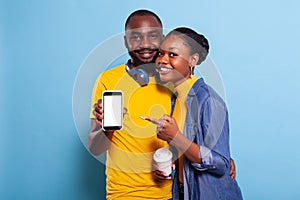 Smiling couple pointing at blank white screen on smartphone