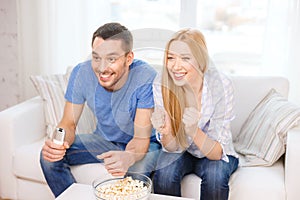 Smiling couple with popcorn cheering sports team