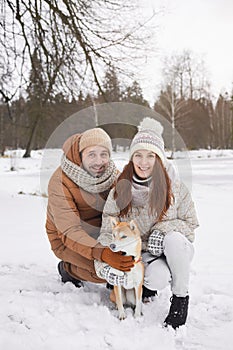 Smiling Couple Posing with Dog in Winter