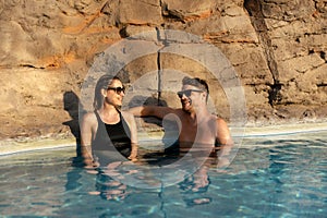 smiling couple relaxing together in spa swimming pool. romantic getaway