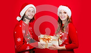 Smiling Couple in Santa's Hat with Christmas gift. Merry Christmas. Happy New Year. Gifting presents. New year sale.