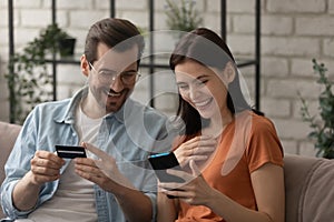 Smiling couple shopping online on cell with card