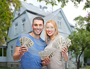 Smiling couple showing money over house background