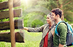 Smiling couple at signpost with backpacks hiking