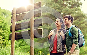 Smiling couple at signpost with backpacks hiking