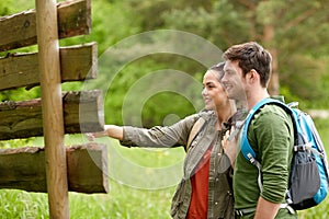 Smiling couple at signpost with backpacks hiking