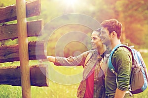 Smiling couple at signpost with backpacks hiking