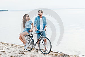 smiling couple sitting on bike on beach