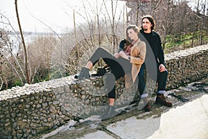 Smiling couple sitting on countryside bulkhead against landscape