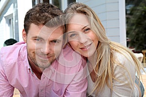 Smiling couple sitting in front of their house