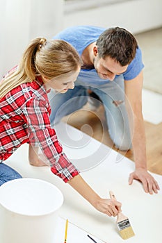 Smiling couple smearing wallpaper with glue