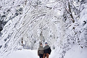 Smiling couple standing in a snow covered forest while hiking