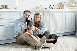 Smiling couple stroking their French bulldog