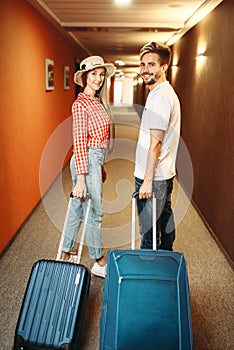 Smiling couple with suitcase in hotel hallway