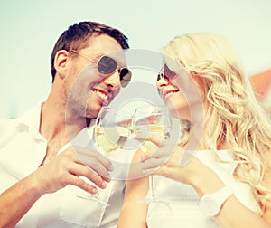 Smiling couple in sunglasses drinking wine in cafe