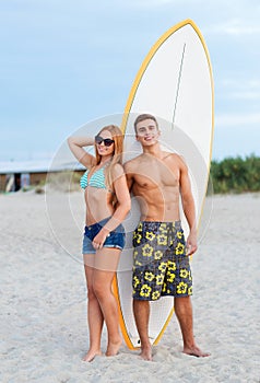 Smiling couple in sunglasses with surfs on beach photo