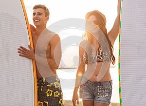 Smiling couple in sunglasses with surfs on beach photo