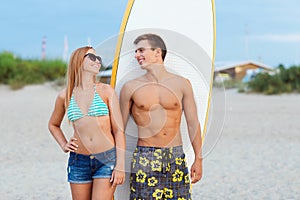 Smiling couple in sunglasses with surfs on beach photo