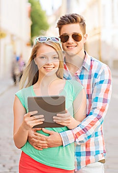 Smiling couple with tablet pc in city