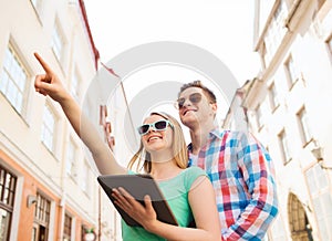 Smiling couple with tablet pc in city