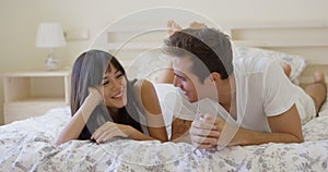 Smiling couple talking while laying down on bed