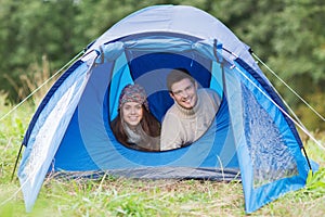 Smiling couple of tourists looking out from tent