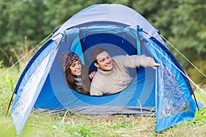 Smiling couple of tourists looking out from tent