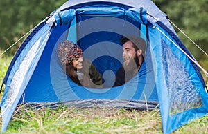 Smiling couple of tourists looking out from tent