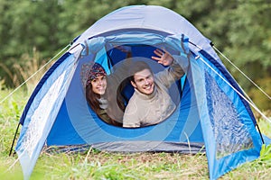 Smiling couple of tourists looking out from tent