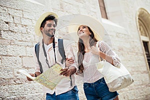 Smiling couple of tourists in sunglasses with map in the city