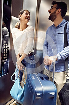 Smiling couple travelers with suitcases in lift