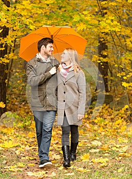 Smiling couple with umbrella in autumn park