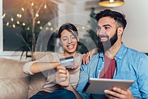 Couple using digital tablet and credit card at home