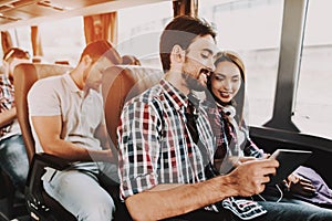 Smiling Couple Using Digital Tablet in Tour Bus