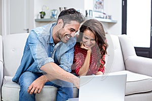 Smiling couple using laptop