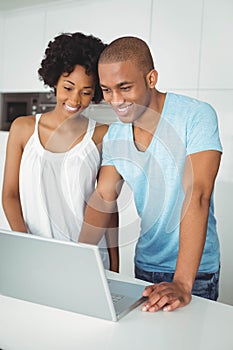 Smiling couple using laptop in kitchen