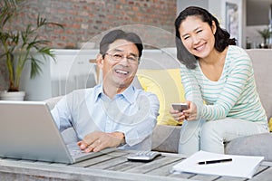 Smiling couple using laptop and smartphone