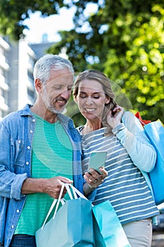 Smiling couple using mobile phone in city