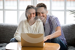 Smiling couple watching funny video on laptop or making videocall photo