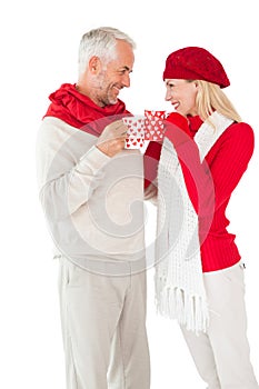 Smiling couple in winter fashion toasting with mugs