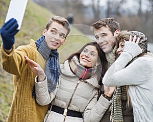 Smiling couples taking self portrait through cell phone in park