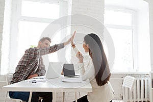 Smiling coworkers giving high five celebrating shared success