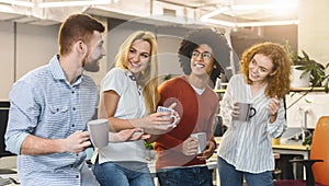 Smiling coworkers having tea during lunch break in coworking space