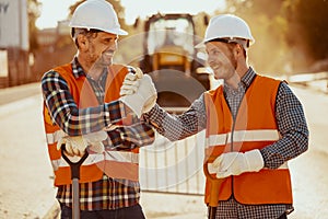 Smiling coworkers in reflective vests and white helmets after roadwork photo