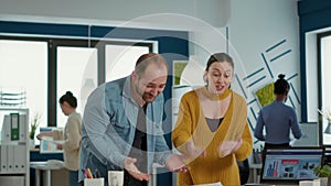 Smiling coworkers in startup office doing high five hand gesture celebrating good sales and high profit