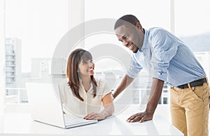 Smiling coworkers using laptop together