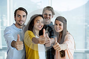 Smiling creative business team showing thumbs up in office