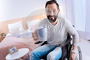 Smiling crippled man suggesting tea