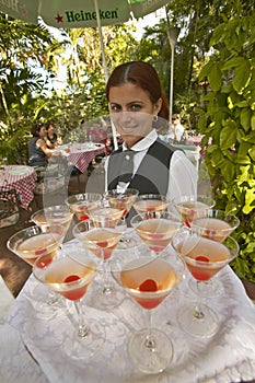 A smiling Cuban woman offering a tray of drinks at tourist restaurant in Havana Cuba